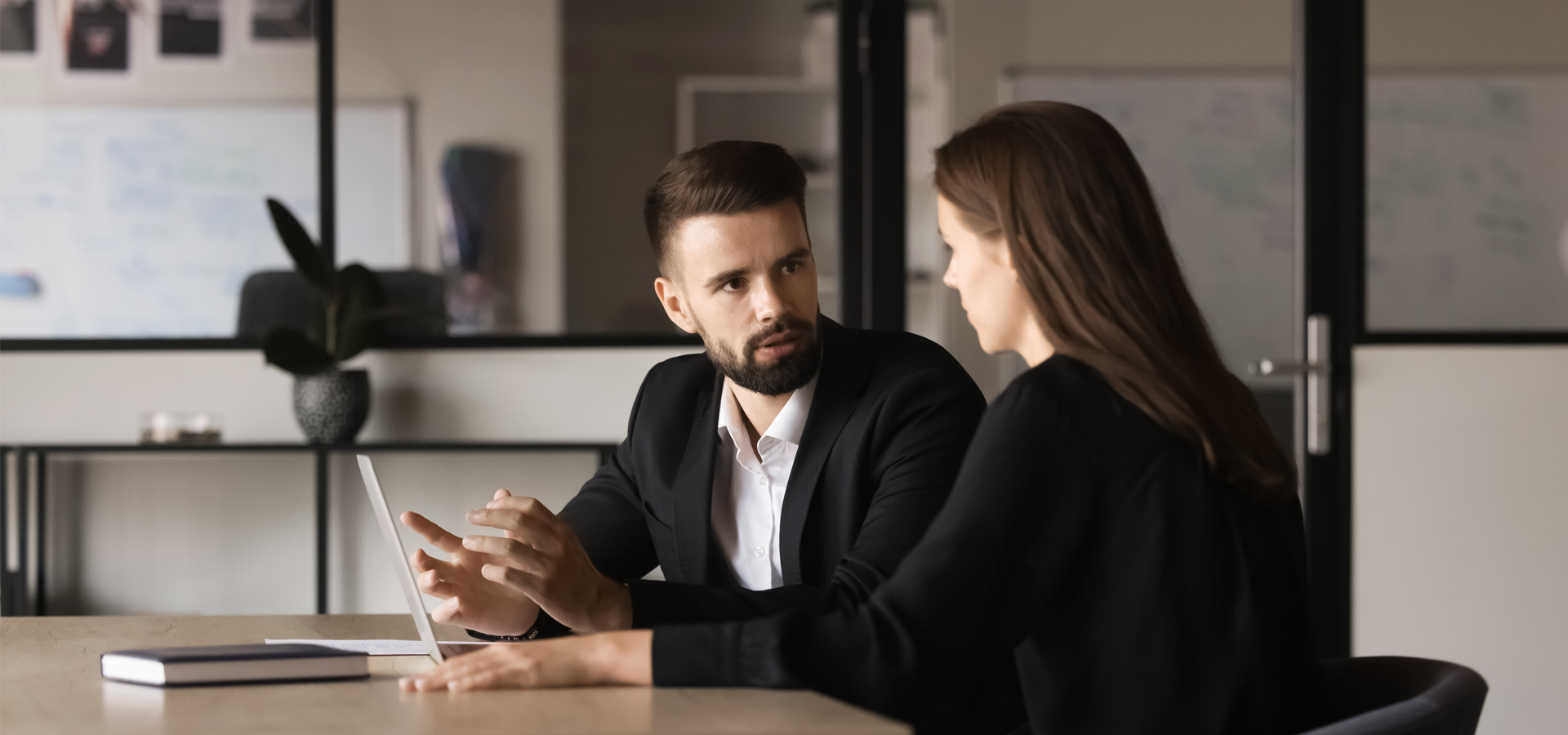 Two professionals discussing taxes over a laptop in an office setting